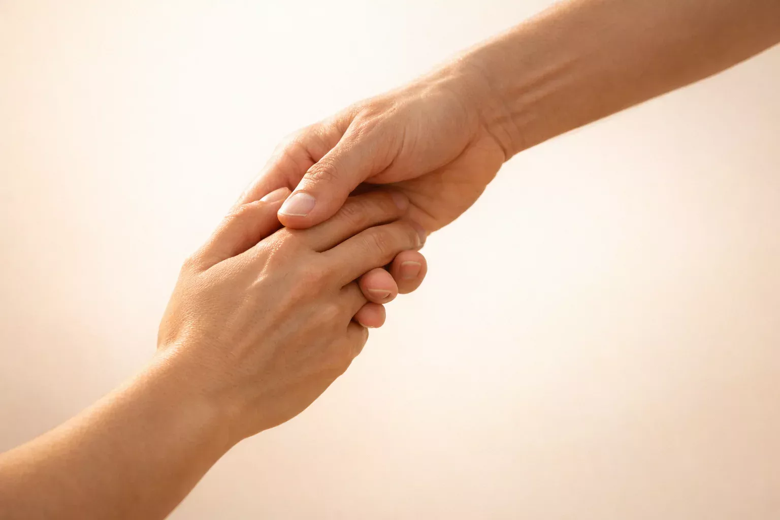 Unterstützende Hand reicht einer anderen Hand als Symbol für Hilfe